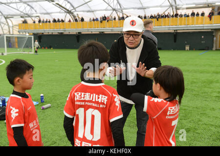 Commentateur de football chinois Dong Lu 'coaching' sous les garçons Football Chine 9 5 football équipe sur leur tournée au Royaume-Uni Banque D'Images