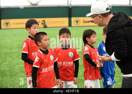 Commentateur de football chinois Dong Lu 'coaching' sous les garçons Football Chine 9 5 football équipe sur leur tournée au Royaume-Uni Banque D'Images