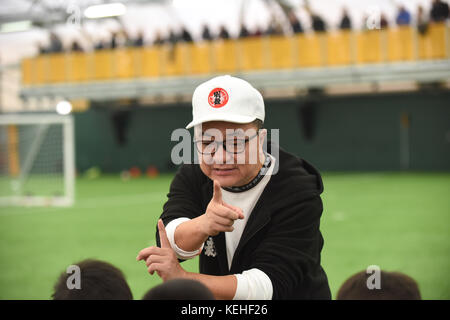 Commentateur de football chinois Dong Lu 'coaching' sous les garçons Football Chine 9 5 football équipe sur leur tournée au Royaume-Uni Banque D'Images