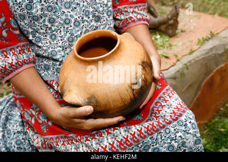 Femme assise et tenant pot d'argile Banque D'Images