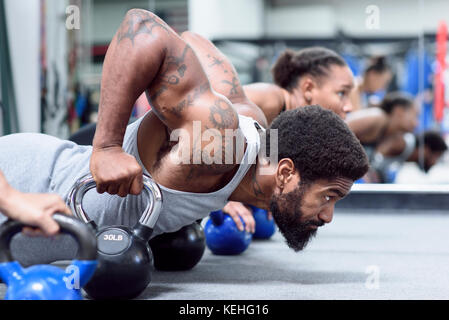 Homme et femme qui font des push-up avec des kettlebells Banque D'Images