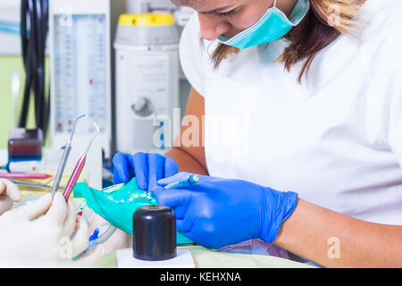 Une jeune femme dentiste dans un manteau blanc et un chapeau médicaux stériles vérifie ses dents pour la carie et la plaque dans le bébé Banque D'Images