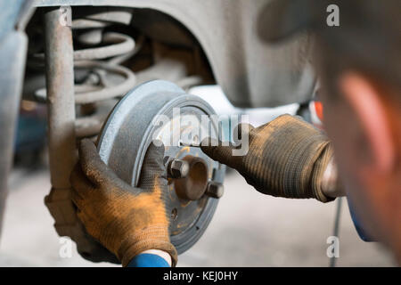 Close-up de frein à tambour de réparation de roue de voiture dans le garage. Banque D'Images