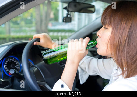 Femme asiatique ivre de boire de l'alcool et la conduite d'une voiture Banque D'Images