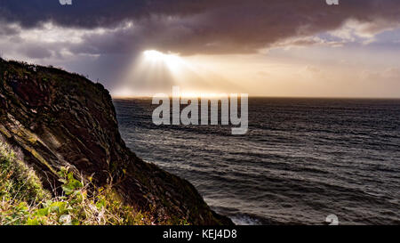 La lumière du soleil se brise à travers les nuages lourds. Vue spectaculaire sur la côte tôt le matin, alors que la tempête atlantique Brian atteint le sud de Cornwall, au Royaume-Uni Banque D'Images