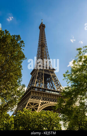 Résumé de la Tour Eiffel à Paris, contre un ciel bleu, entourée d'arbres et d'angle à partir de ci-dessous. Banque D'Images