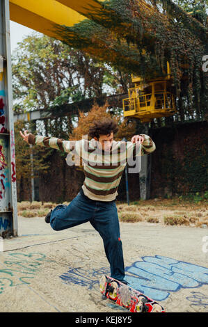 Jeune garçon s'amusant faire acrobating skating dans la zone industrielle juste à l'extérieur de Milan. banlieue banlieues. L'Italie. Banque D'Images