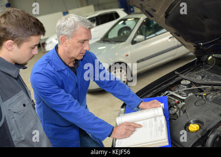 Avec moniteur étudiant la réparation d'une voiture pendant l'apprentissage Banque D'Images
