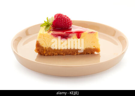 Morceau de gâteau fait maison, décoré avec des framboises et de la menthe sur la plaque sur fond blanc Banque D'Images