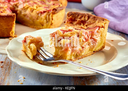 Morceau de gâteau fait maison à la rhubarbe et sa crème anglaise sur table en bois Banque D'Images