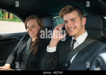 Portrait of Young Smiling Businessman And Businesswoman dans la voiture Banque D'Images