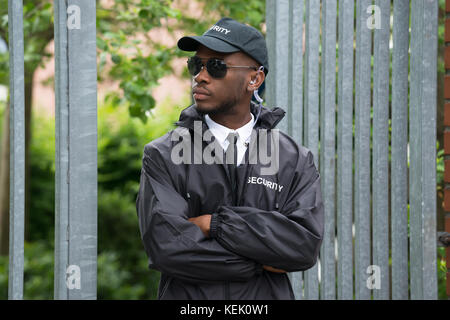 Portrait de jeune homme en uniforme de garde de sécurité noir debout les bras croisés Banque D'Images