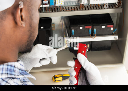 Close-up de jeunes Africains de dénudage des fils électriques électricien Banque D'Images