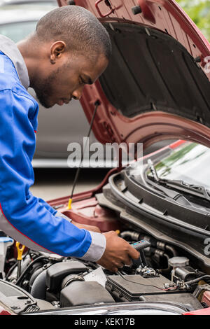 Close-up of male mechanic contrôler avec un multimètre niveau batterie de voiture Banque D'Images