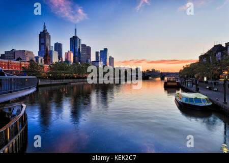 La ville de Melbourne CBD sur front de mer le long de la rivière Yarra avec station Flinders et Prince Bridge au lever du soleil reflétant les lumières dans eaux de Yarra. Banque D'Images