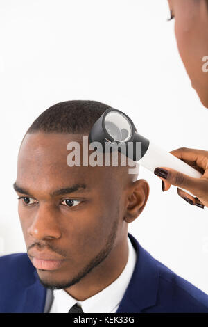 Dermatologue contrôle mole sur african american man in clinic Banque D'Images