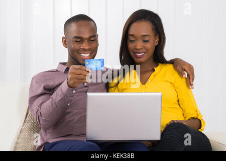 Happy young woman shopping online with credit card at home Banque D'Images