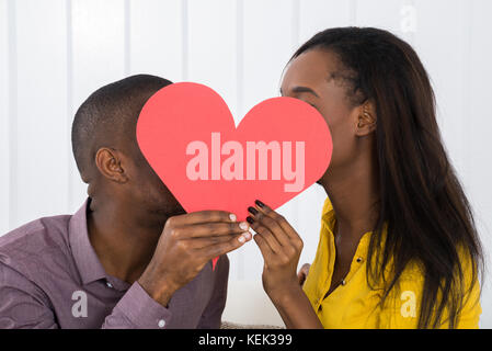 Close-up of young woman Hiding behind forme de coeur Banque D'Images