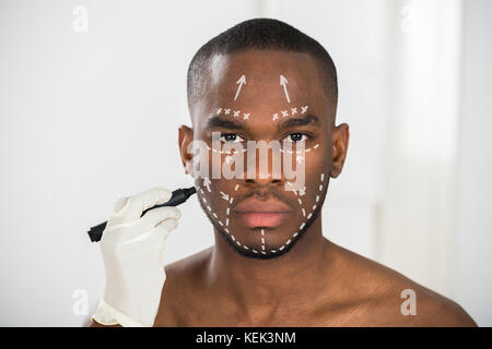 Close-up of Person's Hand Lignes Correction de dessin africain sur le visage de l'Homme Banque D'Images