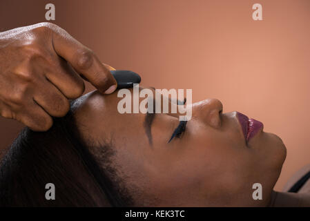 Close-up of Young African Woman Receiving Massage aux pierres chaudes au Spa Banque D'Images