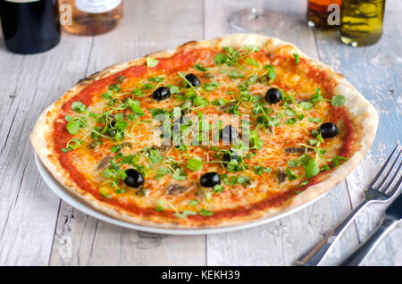 Pizza garni d'anchois, olives noires et cress Banque D'Images