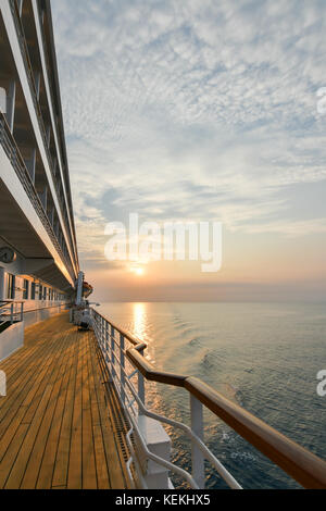Bateau de croisière pont promenade en bois avec beau coucher de soleil et la réflexion sur l'océan. Banque D'Images