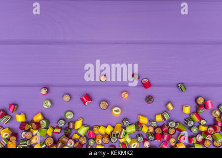 Un cadre fait de bonbons au caramel de couleur sur un fond violet. Copy space Banque D'Images