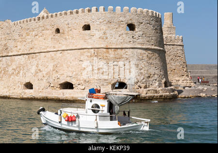 Le port d'Héraklion, Crète, Grèce, octobre 2017. La forteresse vénitienne et le petit bateau de pêche entrant dans le port. Banque D'Images