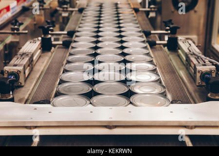 Boîtes en aluminium pour les aliments transformés dans la machine à convoyeur ligne usine fabrication d'aliments en conserve, selective focus et des tons chaleureux. Banque D'Images