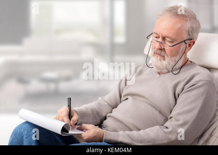 Vieil homme de faire une liste de courses avec un stylo sur du papier pour les vacances Banque D'Images