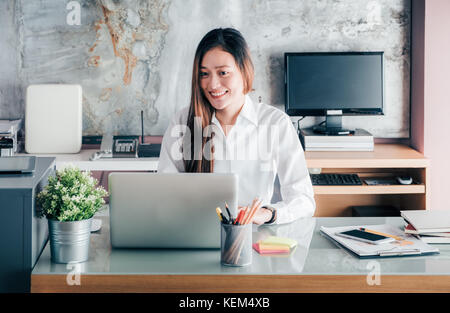 Asie businesswoman looking at laptop computer et visage souriant et de repos avec des professionnels de l'émotion à partir de la bonne nouvelle de la réussite commerciale dans l'accueil Banque D'Images