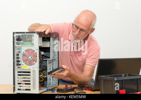 Un homme technicien travaillant sur ordinateur cassé Banque D'Images