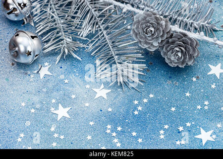 Les branches d'arbre de Noël d'argent avec les cônes et Jingle bells. étoiles filantes sur fond bleu. Banque D'Images