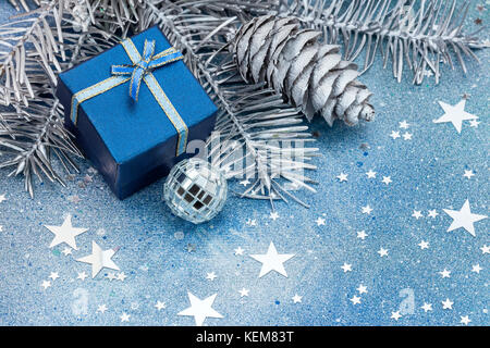 Les branches d'arbre de Noël d'argent avec les cônes, décorations et boîte-cadeau bleu sur fond bleu Banque D'Images