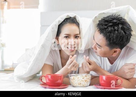 Les jeunes couples asiatiques de prendre le petit déjeuner sur le même lit dans la chambre de maison contemporaine de style moderne concept Banque D'Images