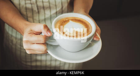 Close-up part d'une serveuse de servir une tasse de café au client. focus sélectif. Banque D'Images