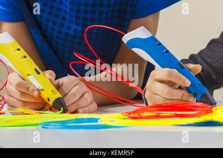 Les enfants les mains avec de l'impression 3d et filaments colorés stylo blanc sur le tableau Banque D'Images