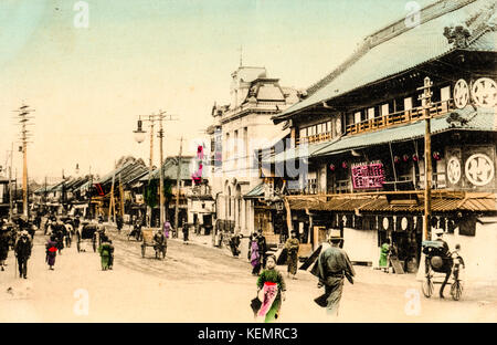 Japon, Yokohama. Vintage, circa 1900, carte postale colorée à la main de scène de rue animée dans la ville japonaise. Bâtiments et personnes. Banque D'Images