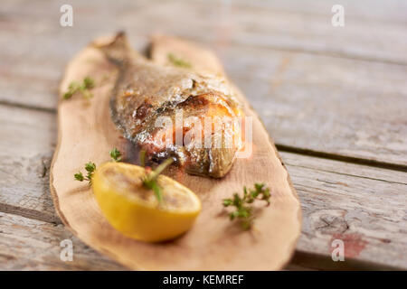 Poissons grillés au citron. dorado dorado rôti poisson avec un morceau de citron sur la table en bois au restaurant. Banque D'Images