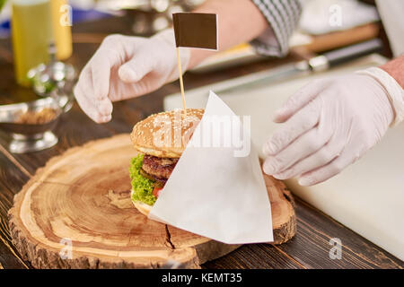 Délicieux cuit chef burger big burger. sur bois naturel. cook burger servant avec serviette. Banque D'Images