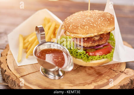 Burger appétissant avec de la viande deux fois. délicieux burger avec frites et sauce sur planche de bois. délicieux dîner dans un restaurant. Banque D'Images