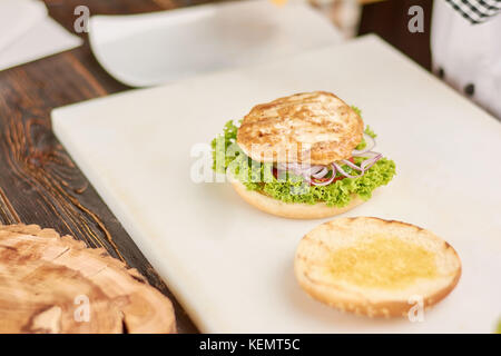 Burger de cuisson avec la viande de poulet. préparer de délicieux burger de poulet avec de la laitue et la tomate. appétissant de la nourriture américaine. Banque D'Images