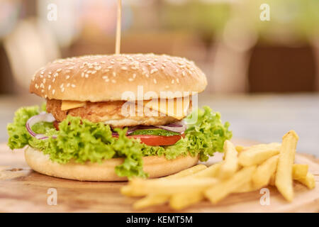 Frais appétissant burger et frites. Poulet, oignon, laitue, tomates, concombres, pommes de terre frites et sandwiches au fromage. Banque D'Images