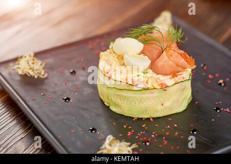 Olivier délicieux avec du saumon, des œufs et du caviar russe traditionnel. olivier salade avec du saumon, des œufs, tobiko, caviar aneth sur plaque. Banque D'Images