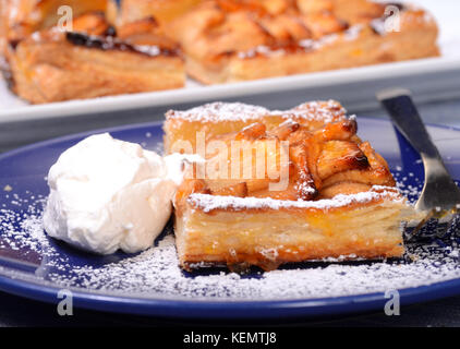 Morceau d'une tarte cuit en croûte avec un lustre d'abricot saupoudrés de sucre en poudre et servi avec de la crème fouettée. Banque D'Images