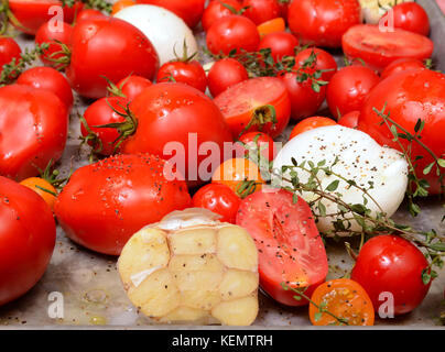 Tomates fraîches, ail, oignons et le thym dans la rôtissoire, prêt à rôtir à faire de délicieux soupe tomate et basilic Banque D'Images