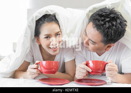 Les jeunes couples asiatiques de prendre le petit déjeuner sur le même lit dans la chambre de maison contemporaine de style moderne concept Banque D'Images