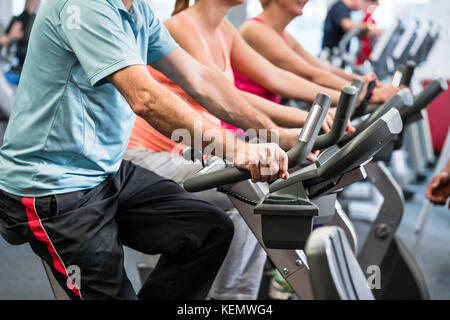 La filature du groupe à la salle de sport sur des vélos de remise en forme Banque D'Images