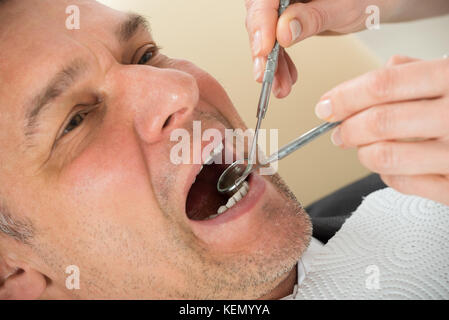 Homme mûr examiné par un dentiste en clinique Banque D'Images