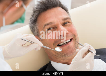 Heureux homme mûr ayant examen dentaire en clinique Banque D'Images